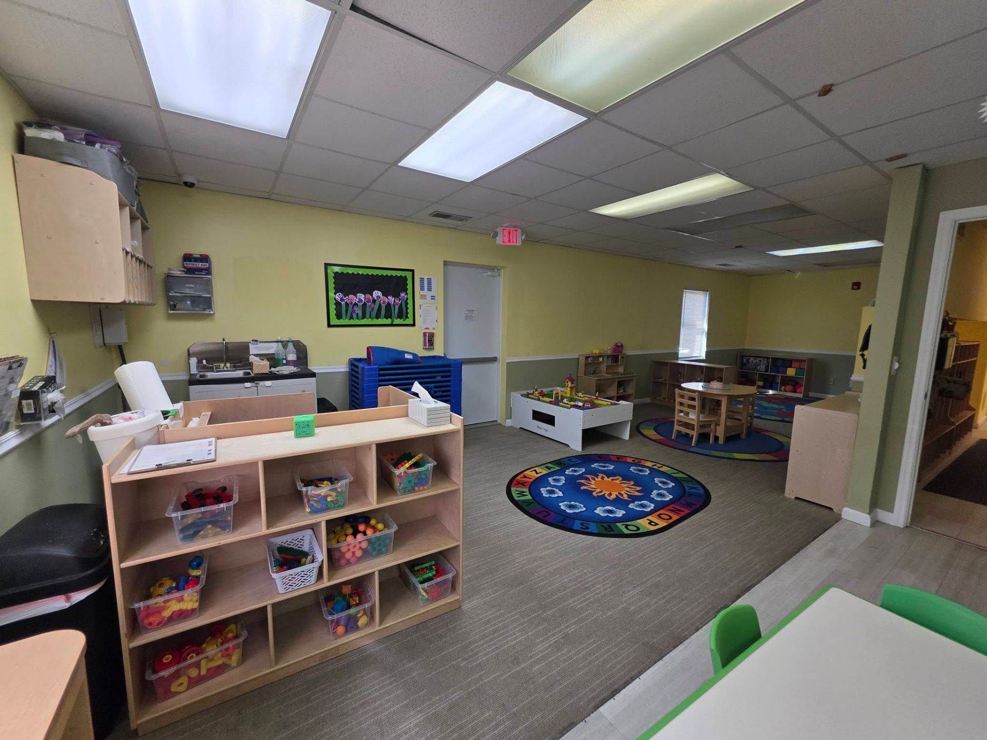 The Caterpillar older toddler room with learning shelves and alphabet rug