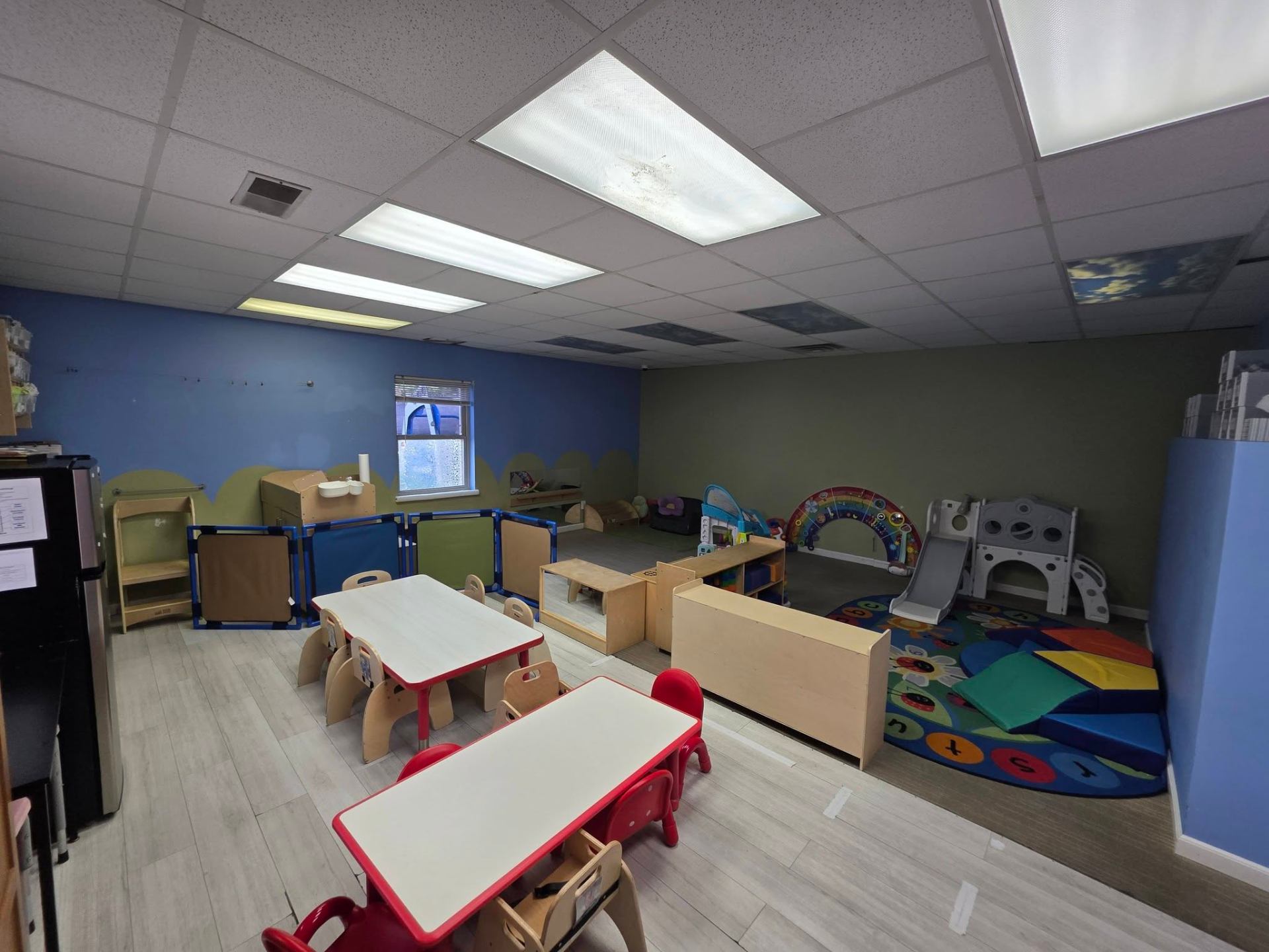 The Ladybug younger toddler room with colorful tables and play area